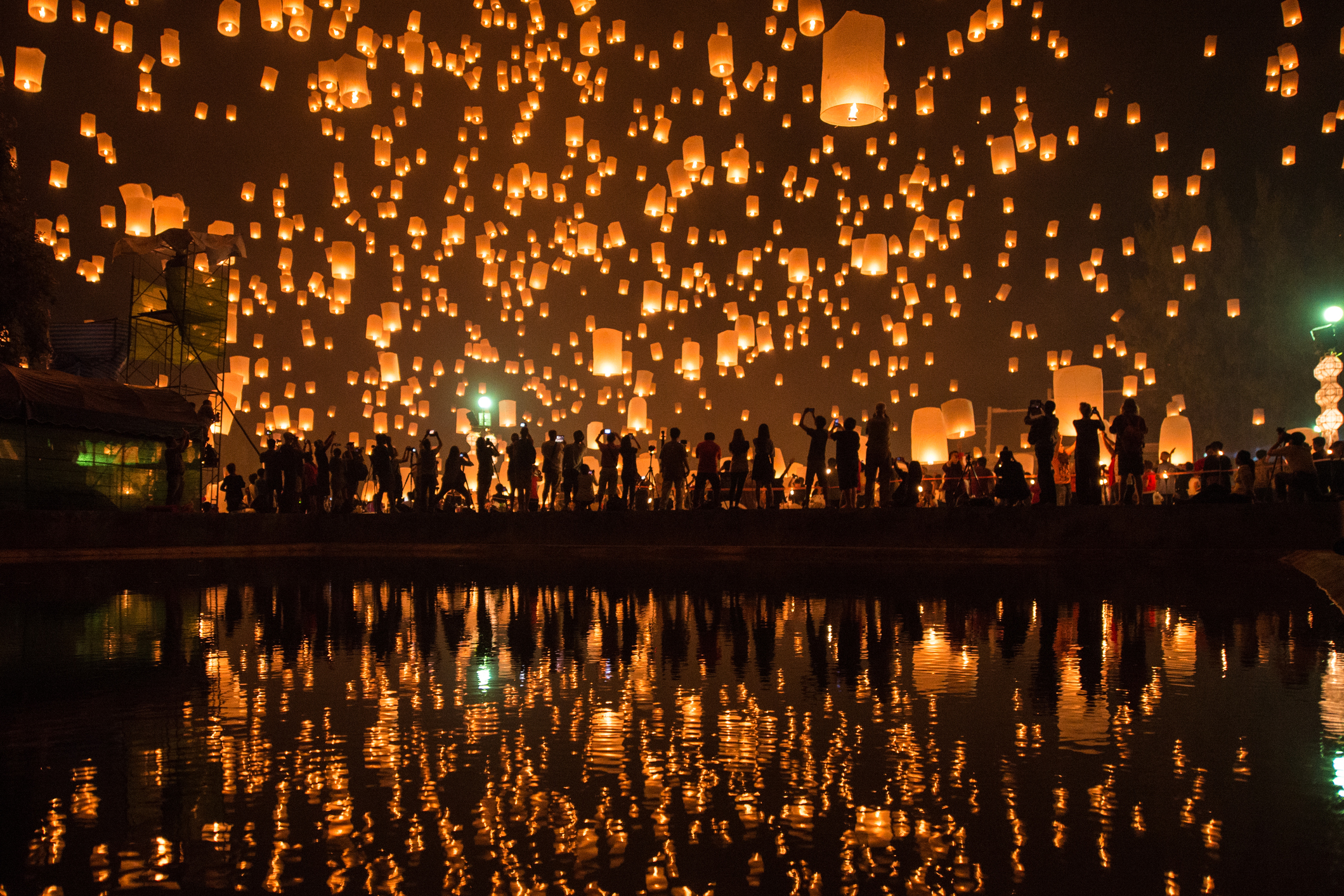Thousands of Lanterns in the sky with the reflection on the water with people watching.Yeepeng festival, Chiangmai, Thailand